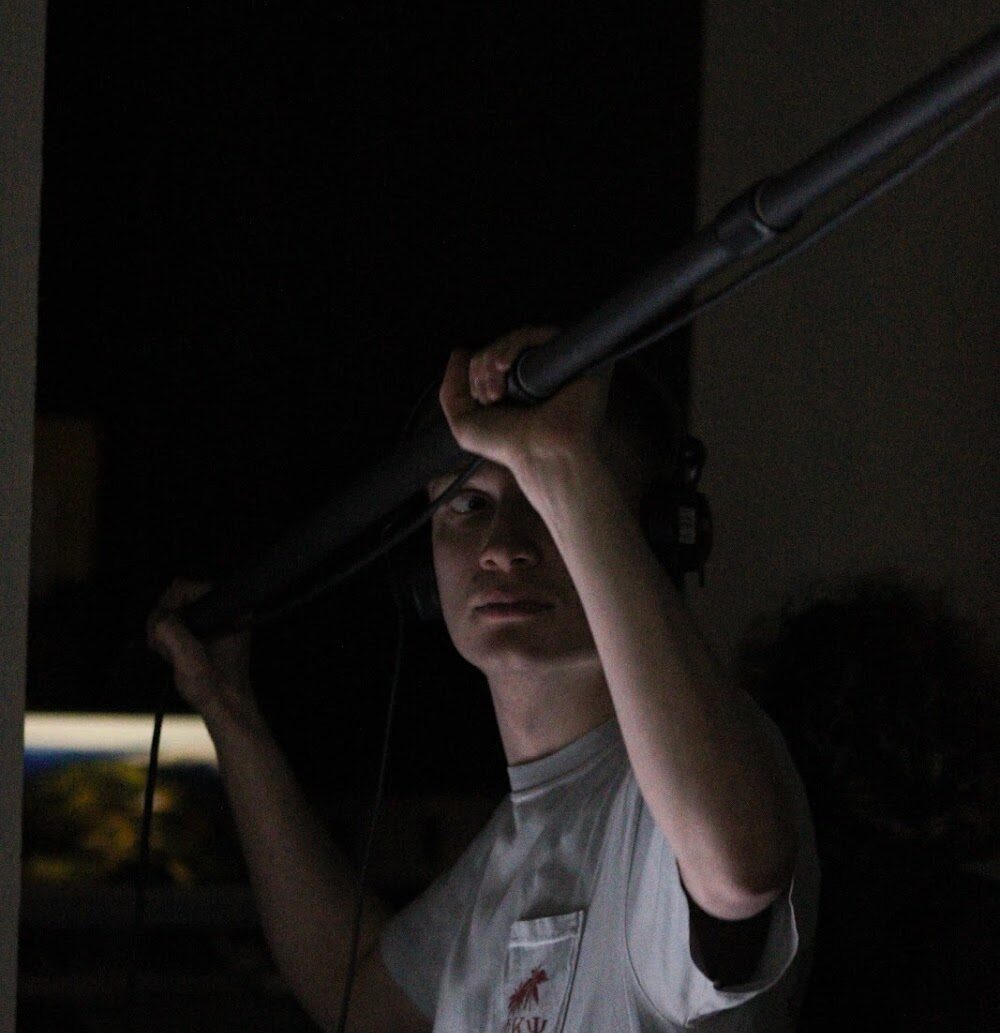 Dan operating a boom microphone on set